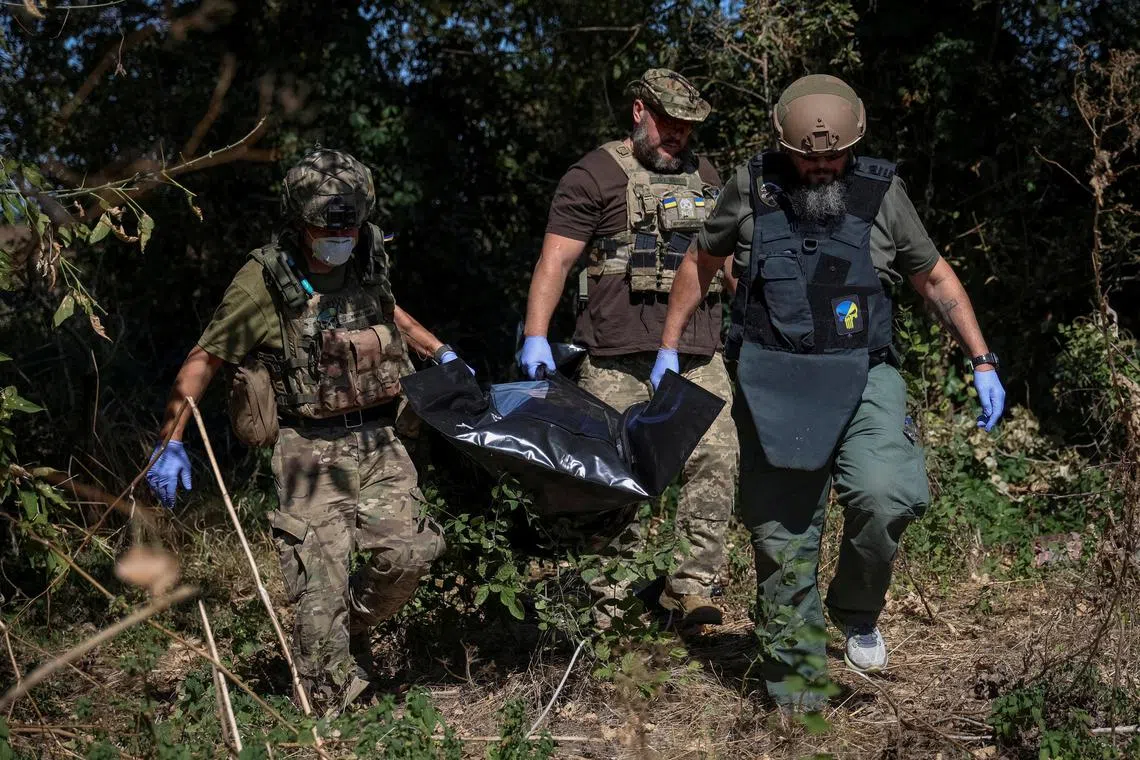 FILE PHOTO: Ukrainian servicemen carry bag containing a body of a dead Russian soldier, amid Russia's attack on Ukraine, in the village of Blahodatne in Donetsk Region Ukraine September 8, 2023. REUTERS/Oleksandr Ratushniak/File Photo