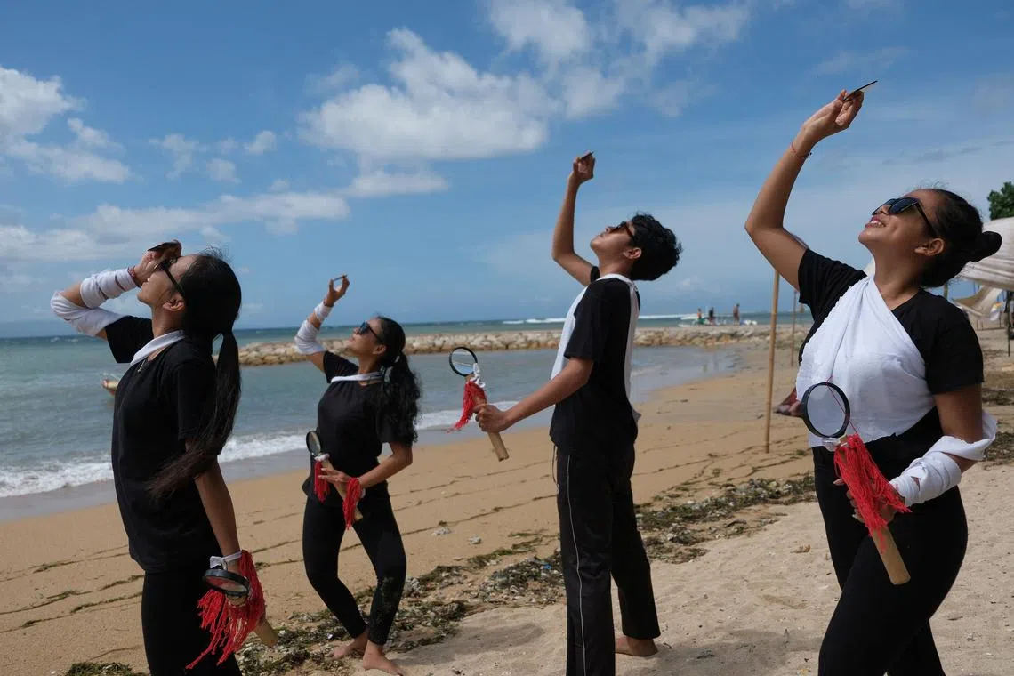 People using welding glass observe a rare hybrid solar eclipse at Segara Ayu beach in Denpasar, Bali, Indonesia, April 20, 2023.