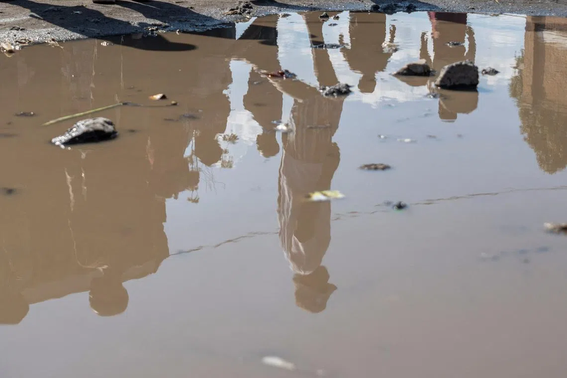 Displaced Congolese people are reflected on a puddle, at the Muchacha primary school, where they live after recently fleeing from their Shasha village following clashes between M23 rebels and the Armed Forces of the Democratic Republic of the Congo (FARDC) in Sake, the Democratic Republic of Congo February 6, 2024. REUTERS/Arlette Bashizi