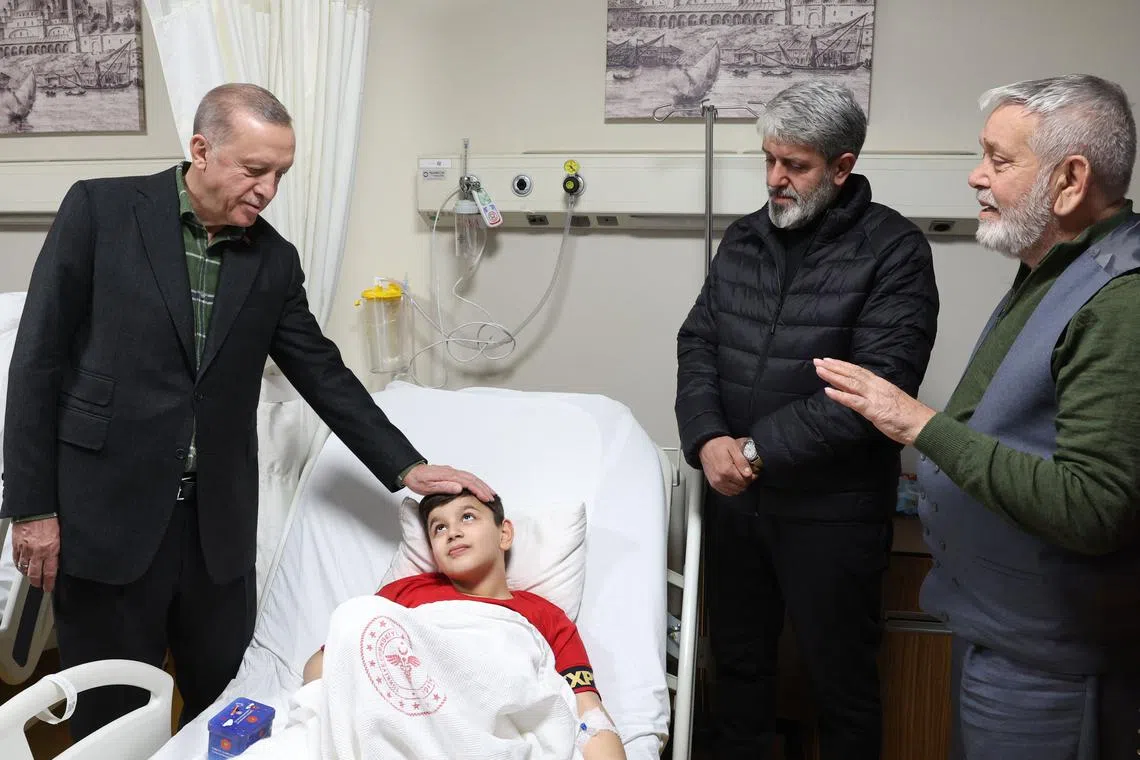 Turkey's President Recep Tayyip Erdogan greets a young boy while visiting wounded and rescued people.