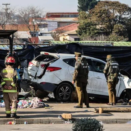Police officers and firefighters working next to a vehicle that struck several people at a street market in Vina del Mar, Chile. At least six people were killed.