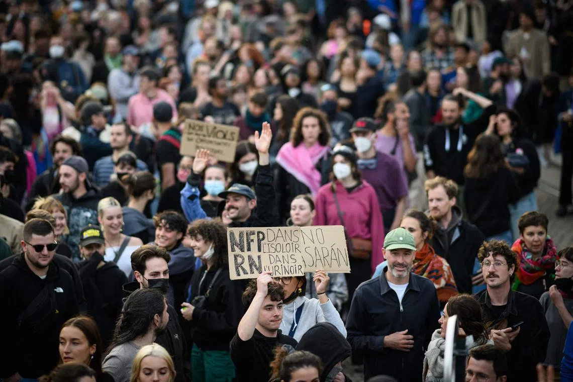 A partcipant holds a placard reading " NFP in the booth, RN in the urinal" during a demonstration in Nantes, western France, on July 7, 2024.