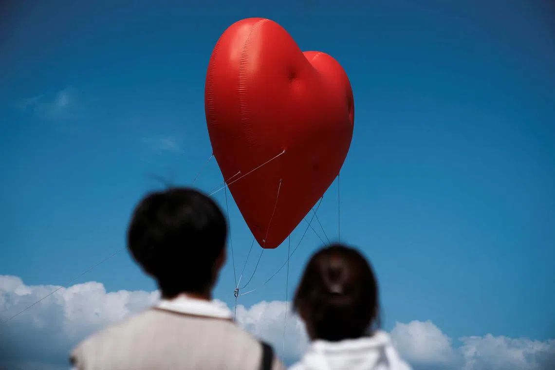 Visitors look at a giant inflatable heart called "Chubby Hearts", an installation by designer Anya Hindmarch, on Valentine's Day in Hong Kong, China February 14, 2024. REUTERS/Lam Yik REFILE - QUALITY REPEAT TPX IMAGES OF THE DAY