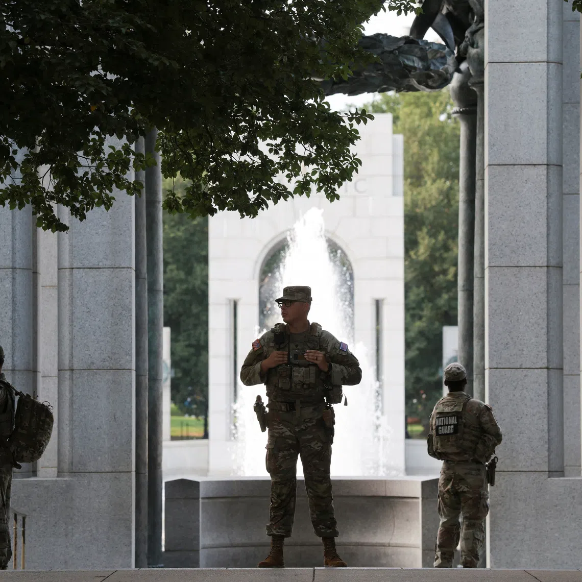 Members of the National Guard stand near the World War II Memorial, after the pool was reportedly vandalised with soap and graffiti.
