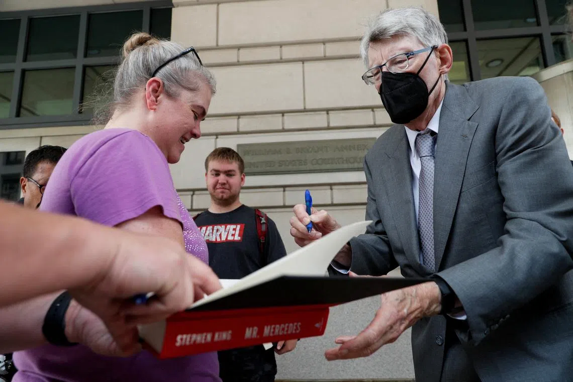Novelist Stephen King gives autographs after testifying in an antitrust case against the merger of Simon & Schuster and Penguin Random House.