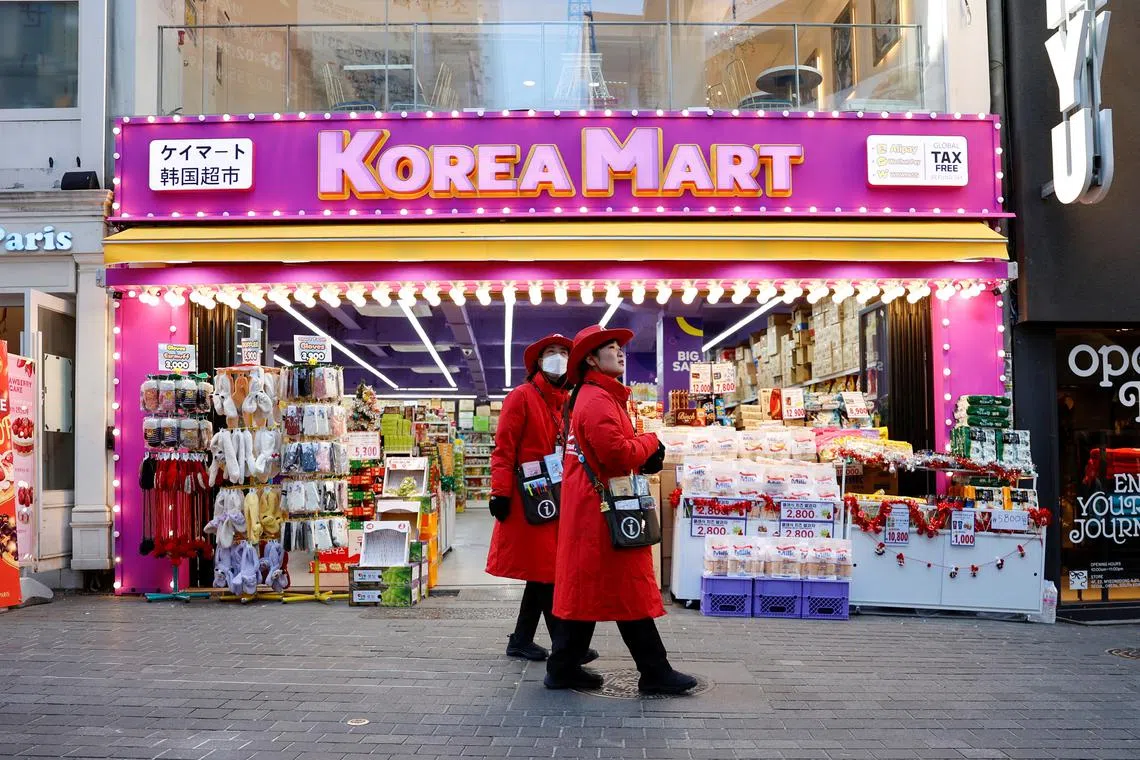FILE PHOTO: Tourist guides walk next to a Korean Mart at Myeongdong Street in Seoul, South Korea, December 5, 2024. REUTERS/Kim Soo-hyeon/File Photo
