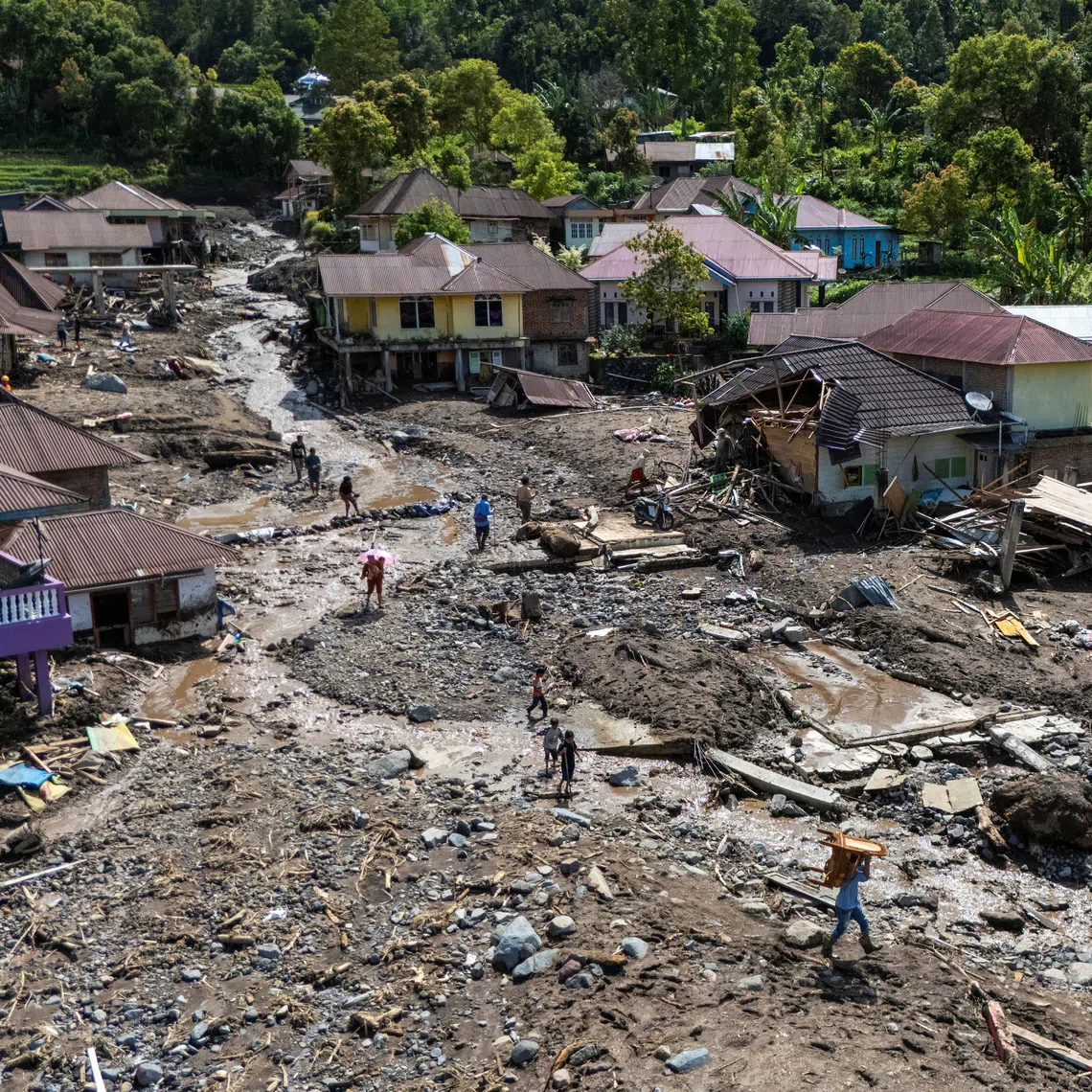 A drone view of local residents carrying their belongings recovered from their homes in an area affected by a deadly landslide following heavy rains in Malalak, Agam regency, West Sumatra province, Indonesia, December 3, 2025. REUTERS/Willy Kurniawan