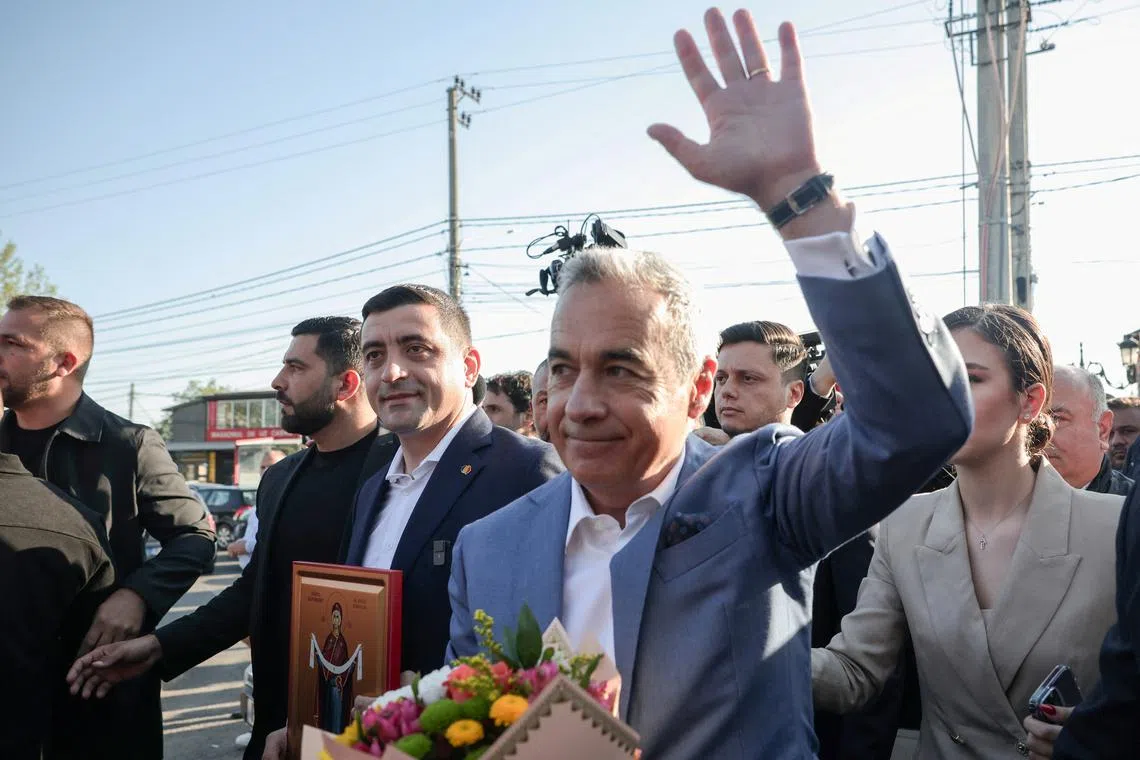 Calin Georgescu waves next to presidential candidate George Simion after casting their votes in country's first round of the presidential election, in Mogosoaia, Romania, May 4, 2025. REUTERS/Louisa Gouliamaki