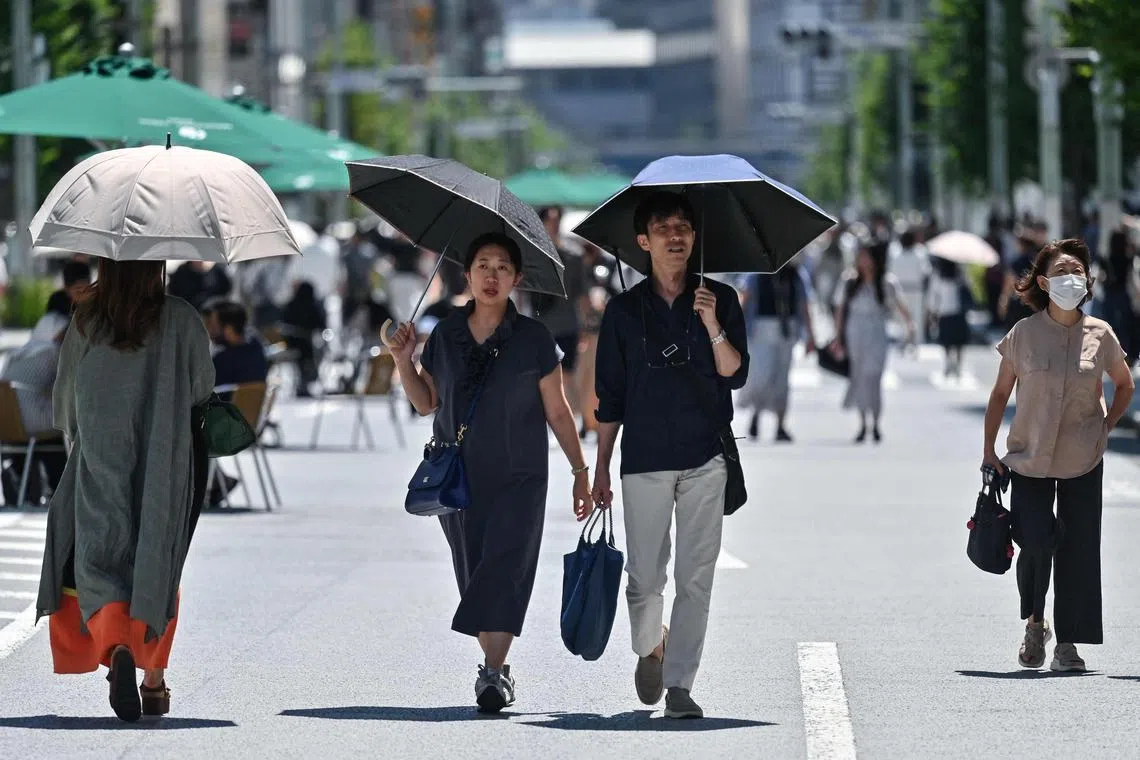 Pedestrians shelter from the sun as the summer heat returns across the country, in the Ginza area of Tokyo on June 16, 2024. (Photo by Richard A. Brooks / AFP)