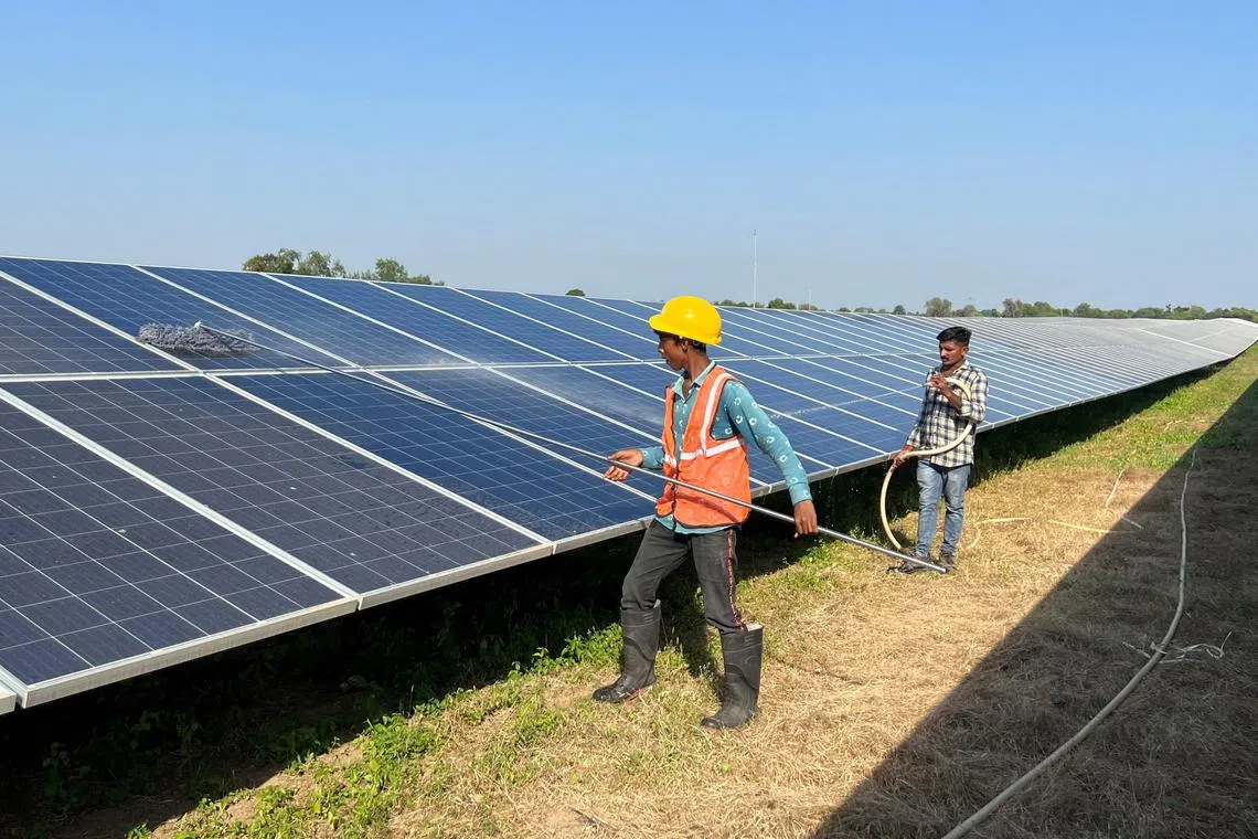 FILE PHOTO: Workers clean panels at a solar park in Modhera, India's first round-the-clock solar-powered village, in the western state of Gujarat, India, October 19, 2022. REUTERS/Sunil Kataria/File Photo