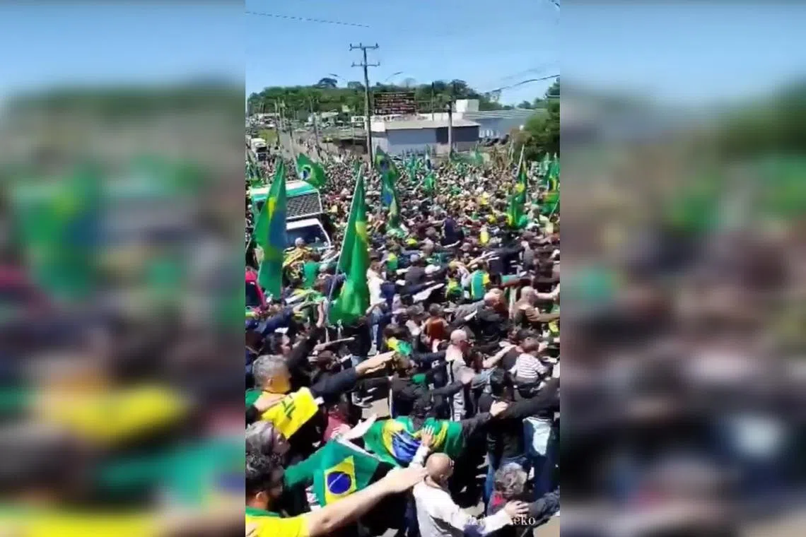 Bolsonaro backers with their right arms outstretched sing Brazil’s national anthem at a protest.