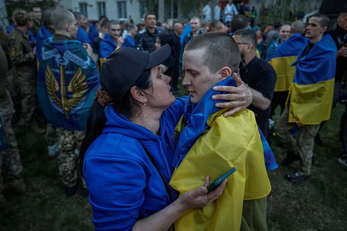 Oleksandr, a Ukrainian prisoner of war, wrapped with his national flag, embracing his mother Olha as he returns after a swap, amid Russia's attack on Ukraine, in an undisclosed location in Ukraine April 19, 2025. 