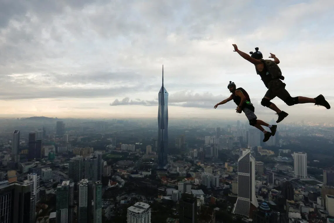Base jumpers are silhouetted as they leap off the Kuala Lumpur Tower during the annual KL Tower International Jump Malaysia 2023 at Kuala Lumpur, Malaysia, Feb 3, 2023.