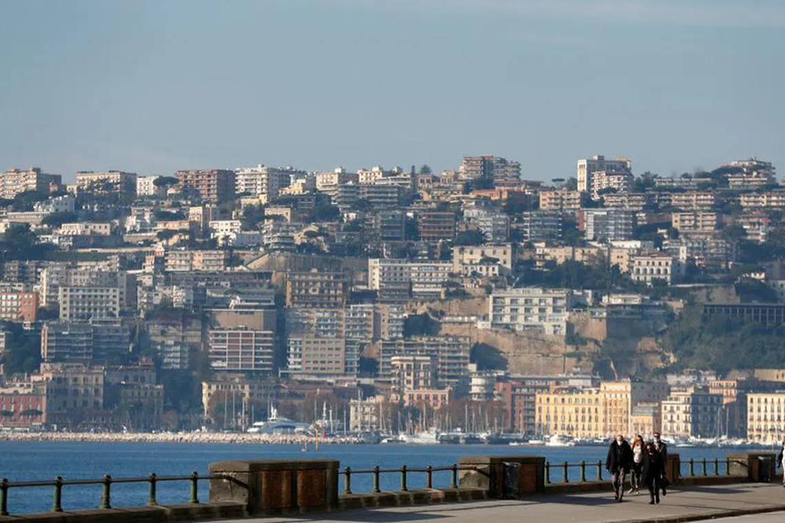 FILE PHOTO: People walk on the waterfront in Naples, Italy November 27, 2020. REUTERS/Yara Nardi