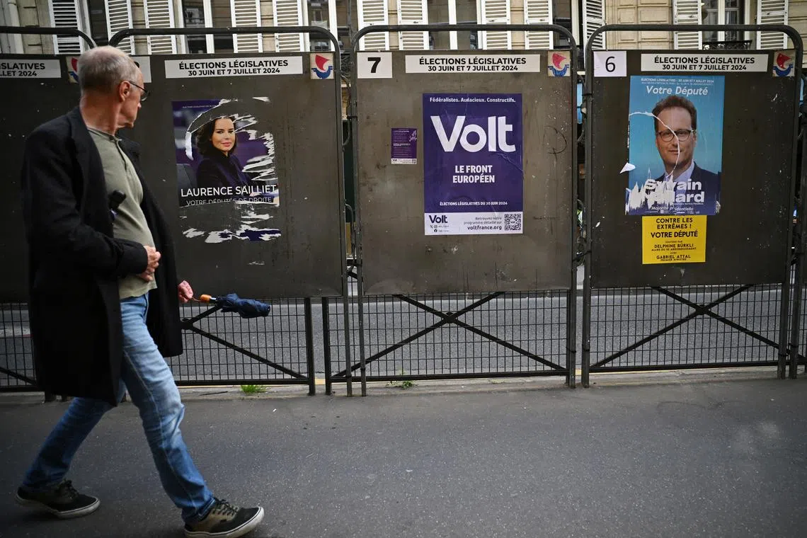 A man walks past election posters outside a polling station, ahead of the French parliamentary elections, in Paris, France, June 22, 2024. REUTERS/Dylan Martinez/File Photo