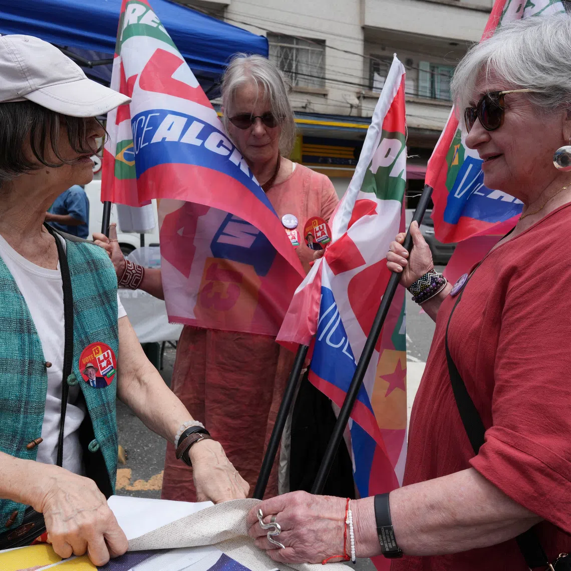 Former political prisoners Rita Sipahi, 88 (R), who shared a cell with former Brazilian President Dilma Rousseff in 1971 during the military dictatorship, Guida Amaral, 75 (C), and Mercia Roberts, 79, hand out campaign material to encourage people to vote for Brazilian President Luiz Inacio Lula da Silva who is seeking re-election, ahead of Brazil's presidential runoff, in Sao Paulo, Brazil, October 15, 2026. REUTERS/Alexandre Meneghini
