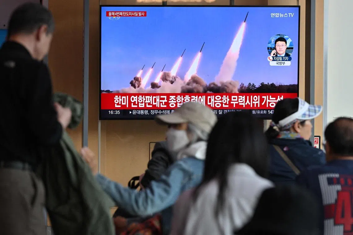 People watching a TV news broadcast with file footage of a North Korean missile test, at a railway station in Seoul on April 22, 2024. 