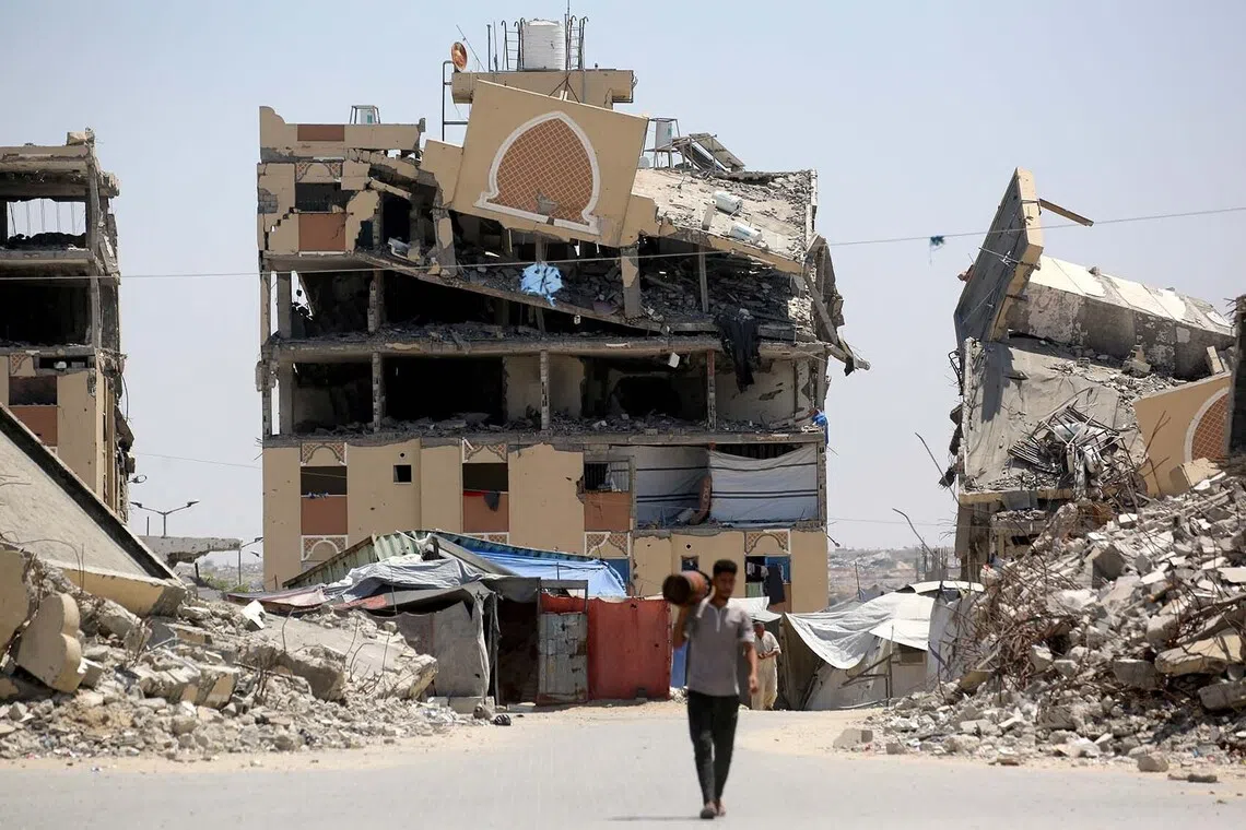 TOPSHOT - An internally displaced Palestinian man walks past the rubble of buildings destroyed by the Israeli military, in Khan Yunis southern Gaza Strip on August 11, 2026. The health ministry in Gaza said on August 11, that the overall death toll since the war broke out on October 7, 2023 now stands at: 73,387. It also said that 1,259 Palestinians have been killed since the ceasefire between Israel and Hamas militants came into effect on October 10. (Photo by Bashar Taleb / AFP)
