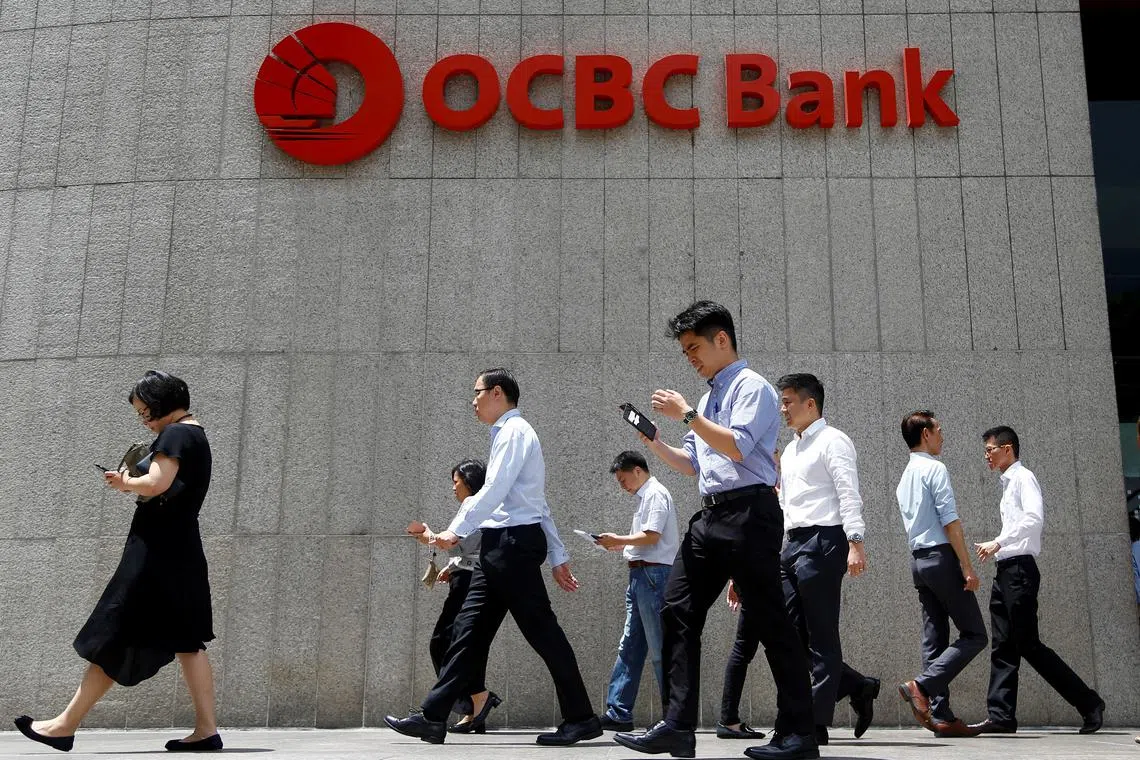 FILE PHOTO: Office workers walk past an OCBC Bank building in Singapore, October 8 2019. REUTERS/Feline Lim/File Photo  GLOBAL BUSINESS WEEK AHEAD