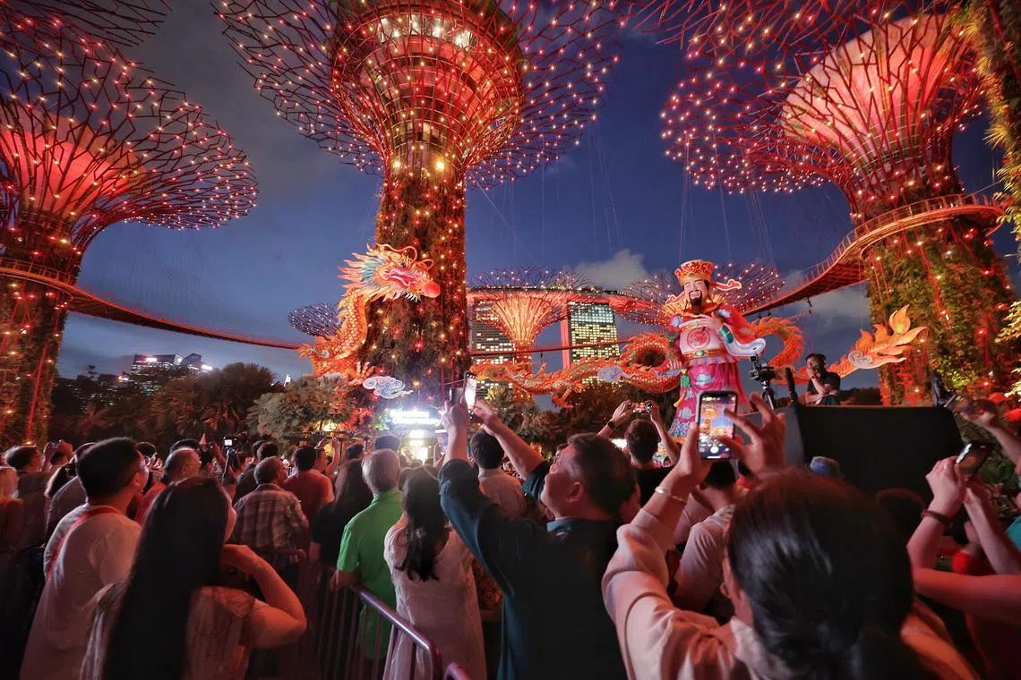 Visitors watching a light show incorporating the Supertrees, a 140m-long dragon lantern and a God of Fortune figurine during the opening ceremony of River Hongbao 2024 at Gardens by the Bay on Feb 8, 2024. ST PHOTO: KEVIN LIM pixrhb08