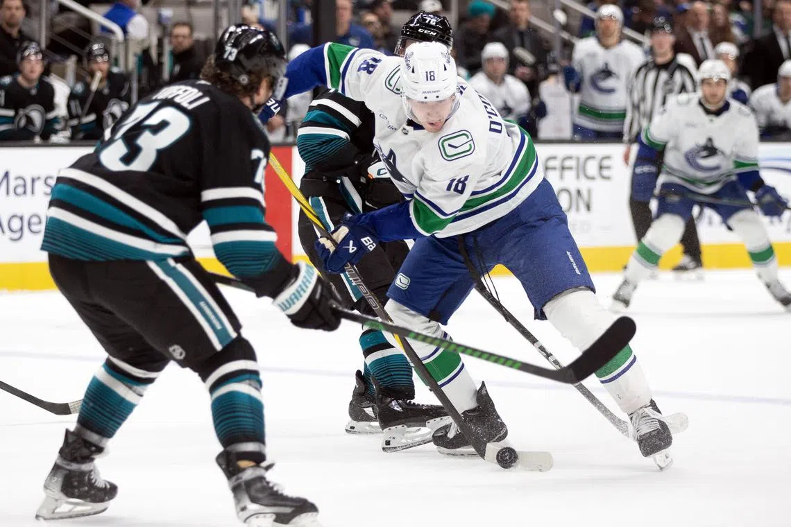 Feb 6, 2025; San Jose, California, USA; Vancouver Canucks left winger Drew O'Connor (18) tries to move the puck past San Jose Sharks center Tyler Toffoli (73) during the first period at SAP Center at San Jose. Mandatory Credit: D. Ross Cameron-Imagn Images