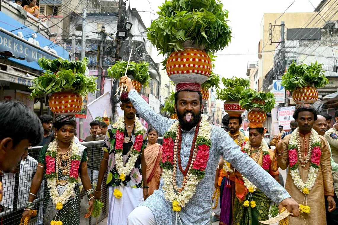 Hindu devotees carring pots with neem leaves and cooked rice, a ritual offering to goddess Kali during Bonalu festival in Secunderabad on July 21, 2024. (Photo by Noah SEELAM / AFP)