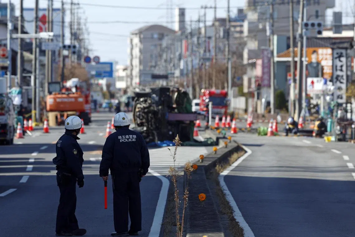 epa11865304 Police officers look at the truck pulled out from a sinkhole without its driver’s cabin, in Yashio, Saitama Prefecture, near Tokyo, Japan, 31 January 2025. Emergency services are searching for a truck driver who fell into a sinkhole on 28 January 2025, but the operation has been hampered by the risk of further collapse. Workers are building a ramp to allow heavy machinery to enter the area in order to rescue the 74 year-old driver.  EPA-EFE/FRANCK ROBICHON