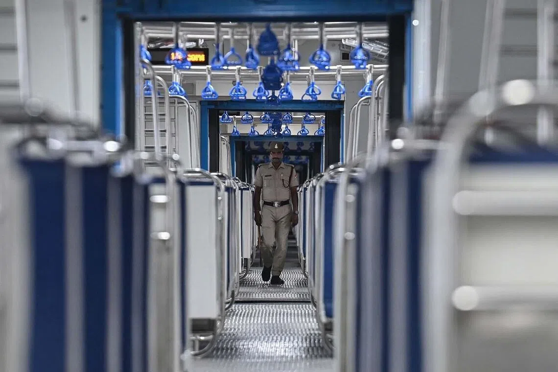 TOPSHOT - A Railway Protection Special Force (RPSF) personnel walks through the coaches of an Indian Railways' hydrogen-powered train at a depot ahead of its launch in Haryana's Jind on July 16, 2026. India launched its first hydrogen-powered train July 17, joining a small group of nations testing the technology as part of efforts to decarbonise rail transport and cut dependence on fossil fuels. (Photo by Arun SANKAR / AFP)