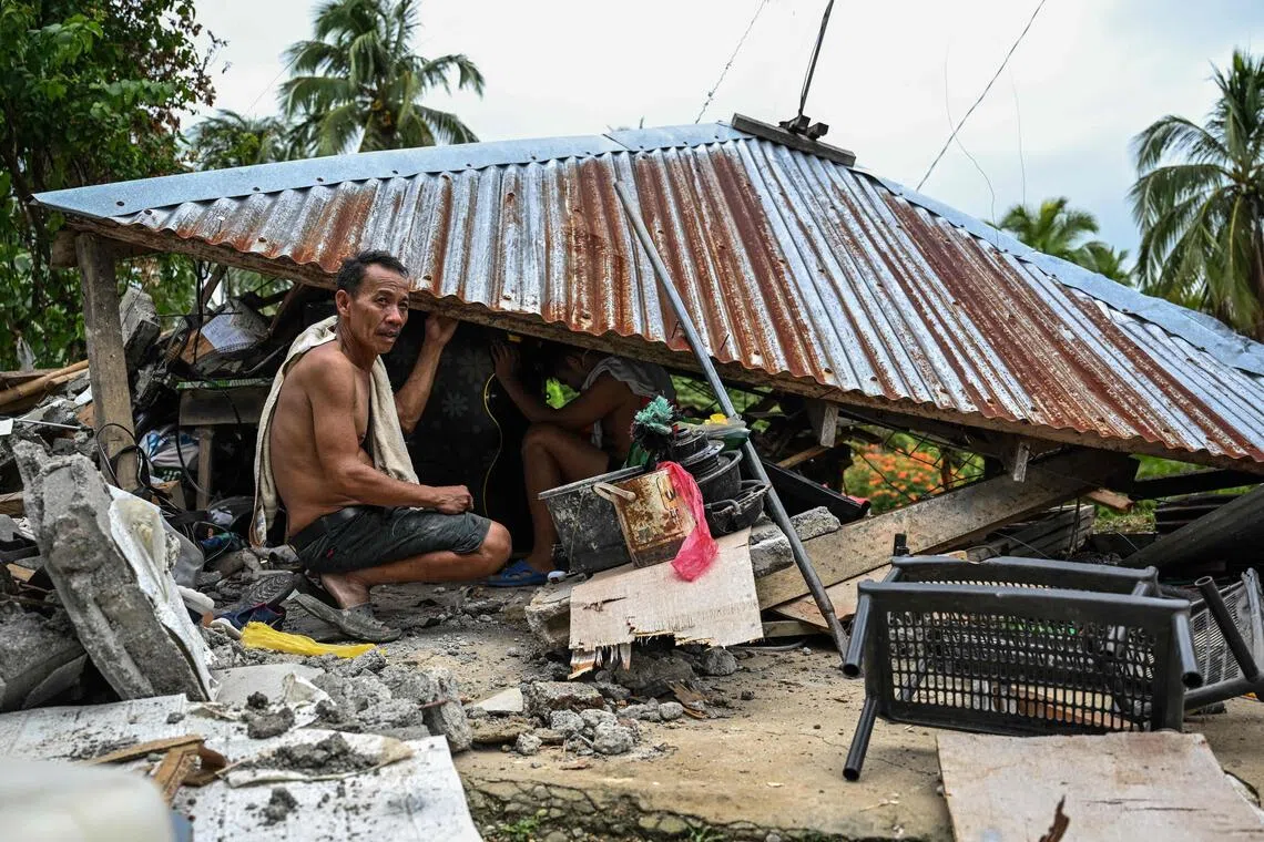 TOPSHOT - Men look for items in a collapsed house in Manay, in the province of Davao Oriental on October 11, 2025, after two powerful quakes struck off the southern Philippines on October 10, killing at least eight people and triggering tsunami warnings. (Photo by Jam STA ROSA / AFP)