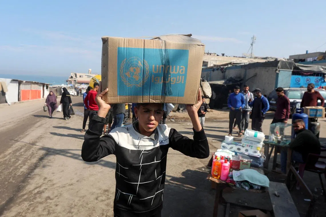 FILE PHOTO: A Palestinian carries an aid box distributed by the United Nations Relief and Works Agency (UNRWA), amid the Israel-Hamas conflict, in Deir Al-Balah, central Gaza Strip, November 4, 2024. REUTERS/Ramadan Abed/File Photo