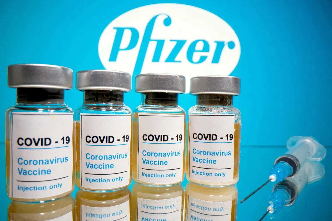 FILE PHOTO: Vials with a sticker reading, \"COVID-19 / Coronavirus vaccine / Injection only\" and a medical syringe are seen in front of a displayed Pfizer logo in this illustration taken October 31, 2020. REUTERS/Dado Ruvic/File Photo
