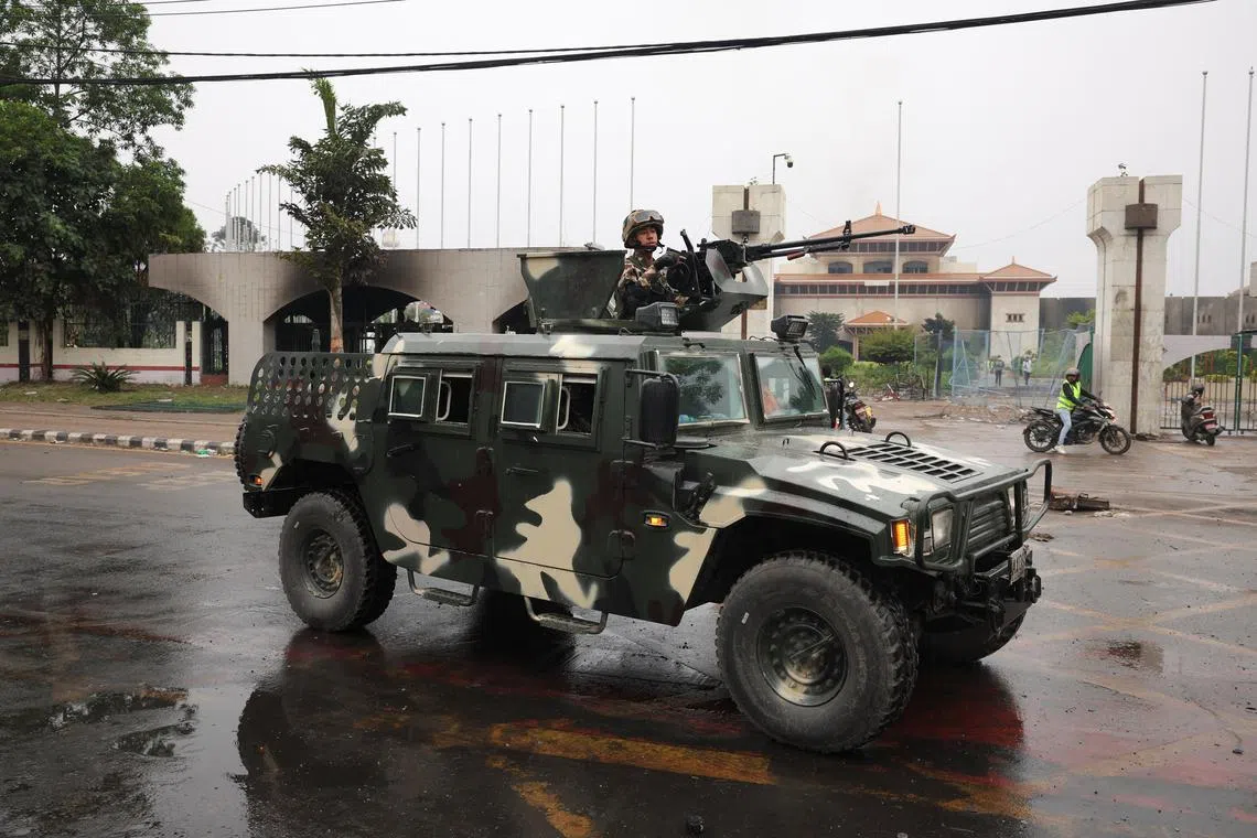 A Nepali Army solider stands in an armoured vehicle driving past the Parliament house which was set on fire by protesters, following Monday's killing of 19 people after anti-corruption protests that were triggered by a social media ban, which was later lifted, in Kathmandu, Nepal, September 10, 2025. REUTERS/Adnan Abidi