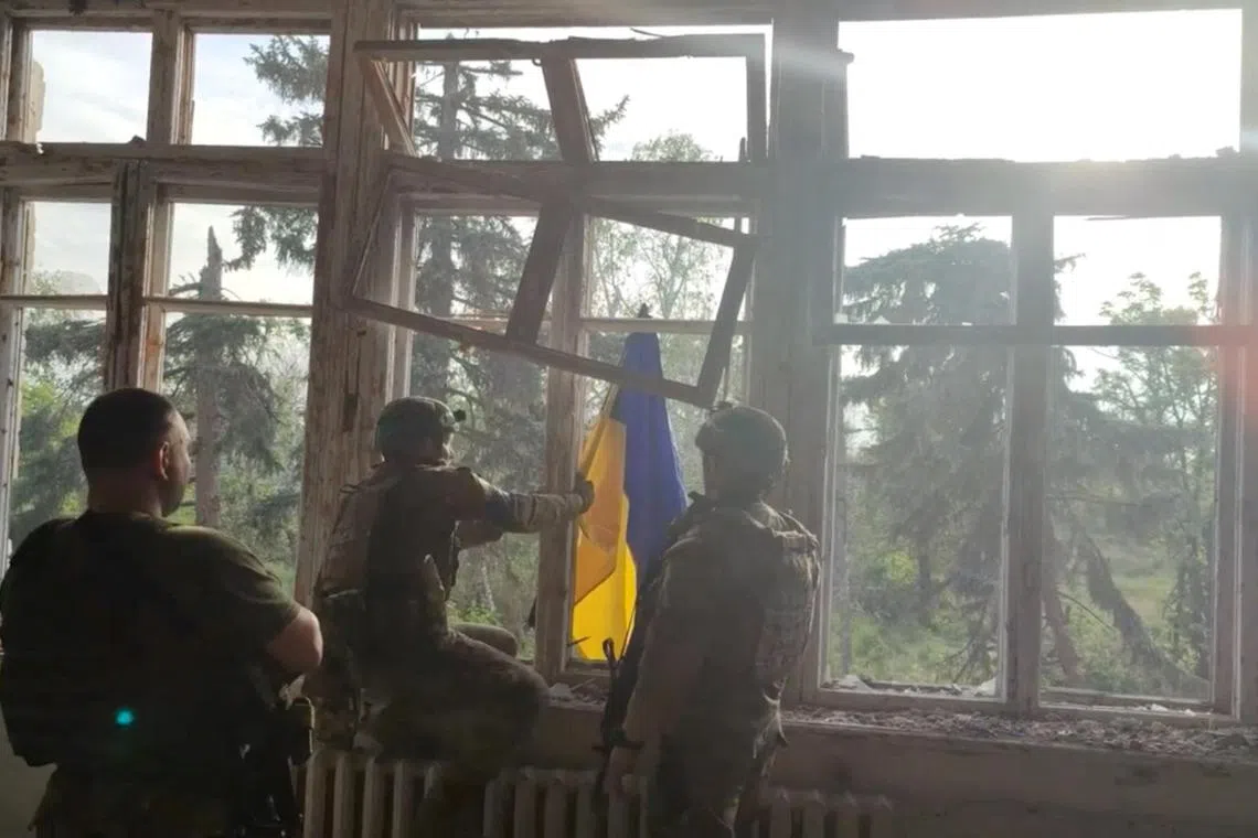 Ukrainian soldiers place a Ukrainian flag at a building, during an operation that claims to liberate the first village amid a counter-offensive, in a location given as Blahodatne, Donetsk Region, Ukraine, in this screengrab taken from a handout video released on June 11, 2023. 68th Separate Hunting Brigade 'Oleksy Dovbusha'/Handout via REUTERS    THIS IMAGE HAS BEEN SUPPLIED BY A THIRD PARTY. NO RESALES. NO ARCHIVES. MANDATORY CREDIT. REUTERS WAS NOT ABLE TO INDEPENDENTLY VERIFY THE LOCATION OF THE VIDEO AND THE DATE IT WAS FILMED.
