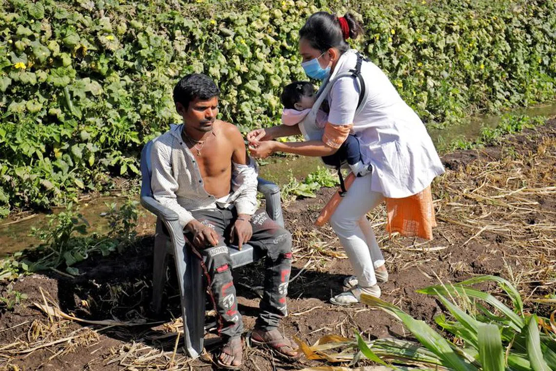 FILE PHOTO: Asmita Koladiya, 29, a healthcare worker, carrying her eight-month-old daughter Jiyanshi Gaurang, gives a dose of vaccine against the coronavirus disease (COVID-19) to a villager in Lodhida village in Rajkot district in the western state of Gujarat, India, February 2, 2022. REUTERS/Amit Dave/File Photo