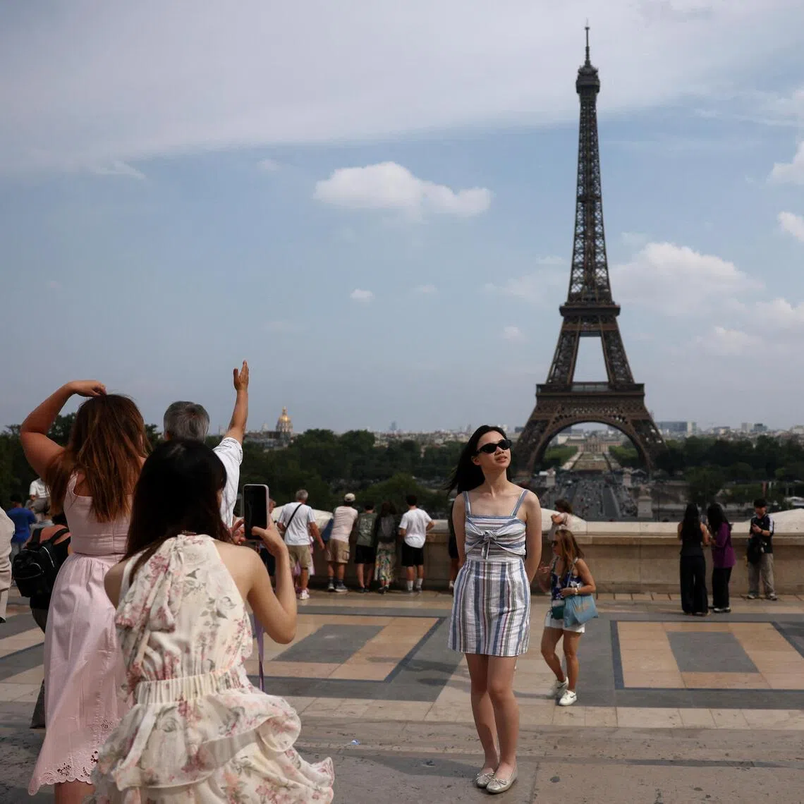 Tourists posing for photos at Trocadero square in Paris, France.