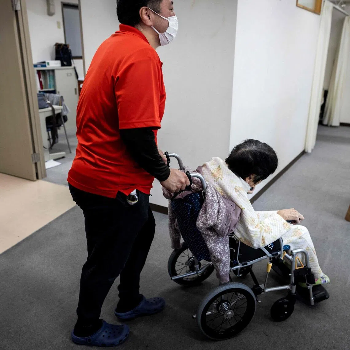 A caretaker wheels an elderly woman after a bath at a day care facility for senior citizens in Tokyo.