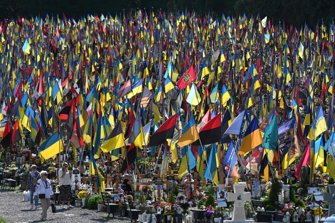 TOPSHOT - People visit Lychakiv Cemetery to pay tribute to fallen Ukrainian soldiers on Ukraine's Independence Day in Lviv, on August 24, 2026, amid the Russian invasion of Ukraine. (Photo by YURIY DYACHYSHYN / AFP)