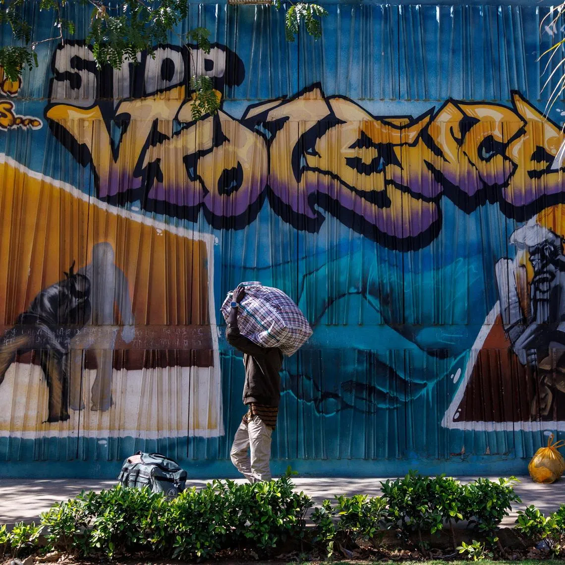 A student carries a bag with his belongings as he walks past a graffiti mural reading “Stop Violence” outside the Cheikh Anta Diop University campus that  was closed today until further notice after clashes with security forces left one student dead during protests in which demonstrators have been demanding stipends and other financial support amid the government’s ongoing fiscal challenges in Dakar, Senegal, February 10, 2026.REUTERS/Zohra Bensemra