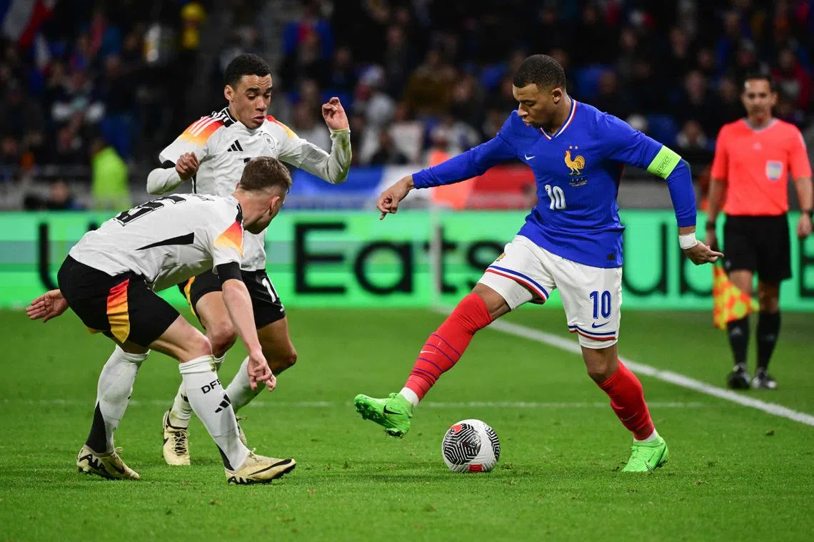 France's Kylian Mbappe coping with the attention from Germany's Serge Gnabry and Joshua Kimmich during a friendly in March. 