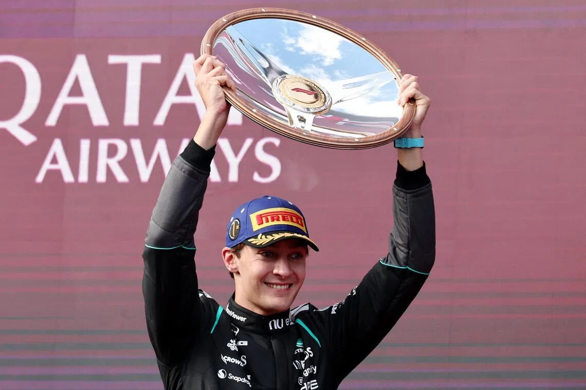 Mercedes' George Russell celebrates with the trophy on the podium after winning the Australian Grand Prix.
