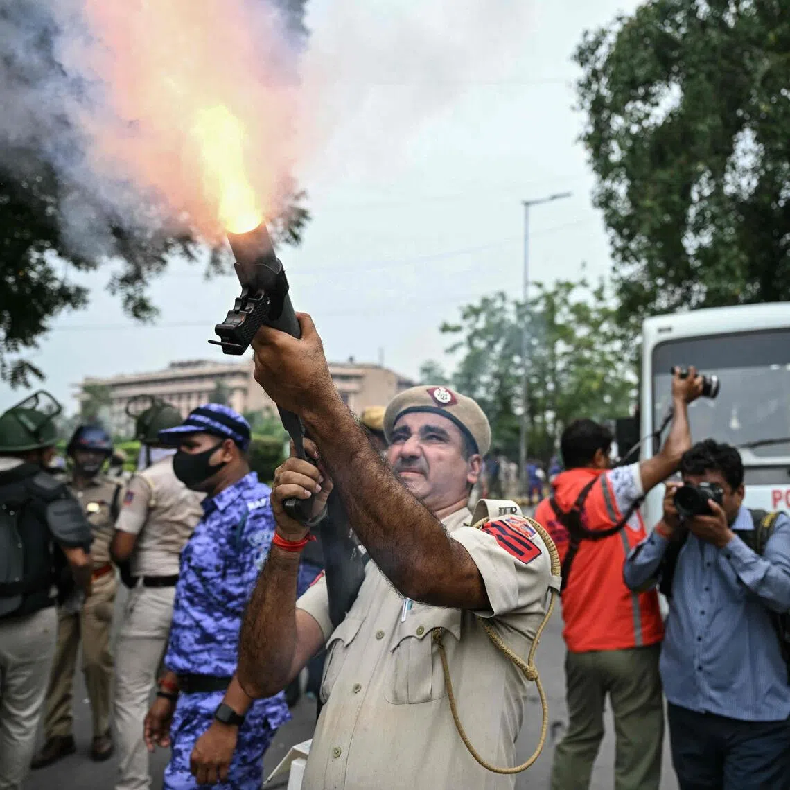 A policeman fires tear gas shells to disperse supporters of the Cockroach Janta Party during a protest demanding the resignation of India’s Education Minister Dharmendra Pradhan.