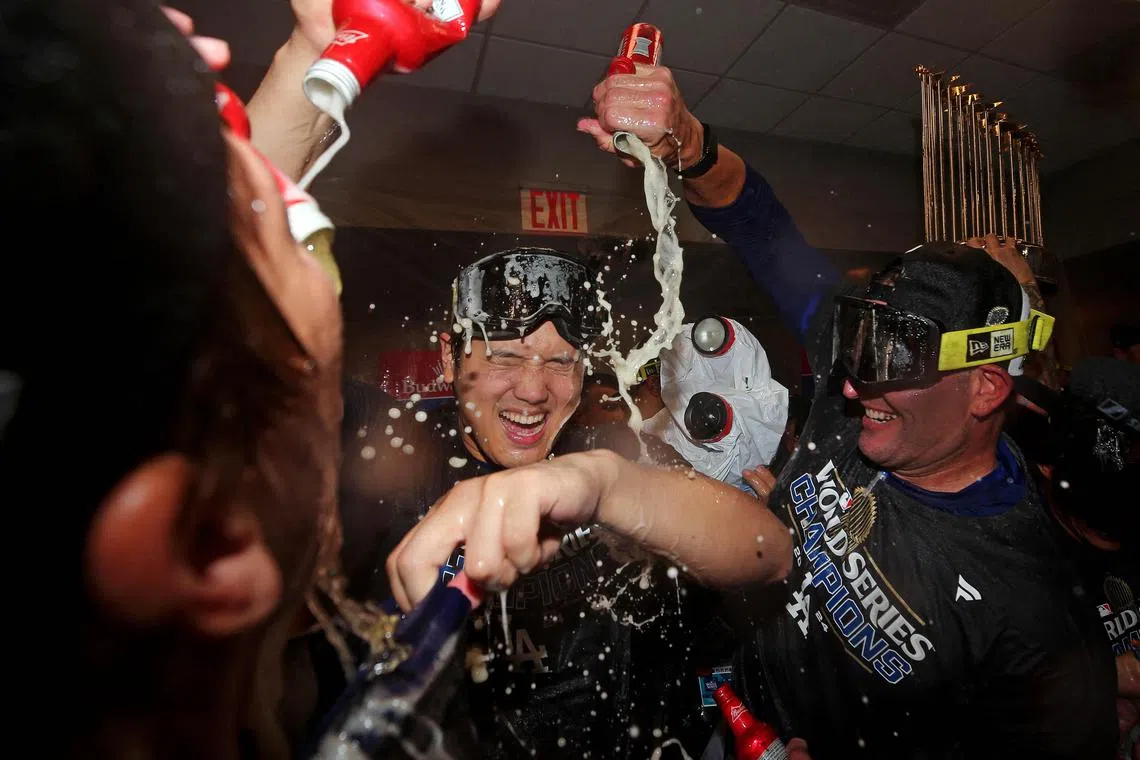 Shohei Ohtani celebrating with his teammates in the locker room with the world series trophy in the background after the Los Angeles Dodgers beat the New York Yankees to seal their title on Oct 30.