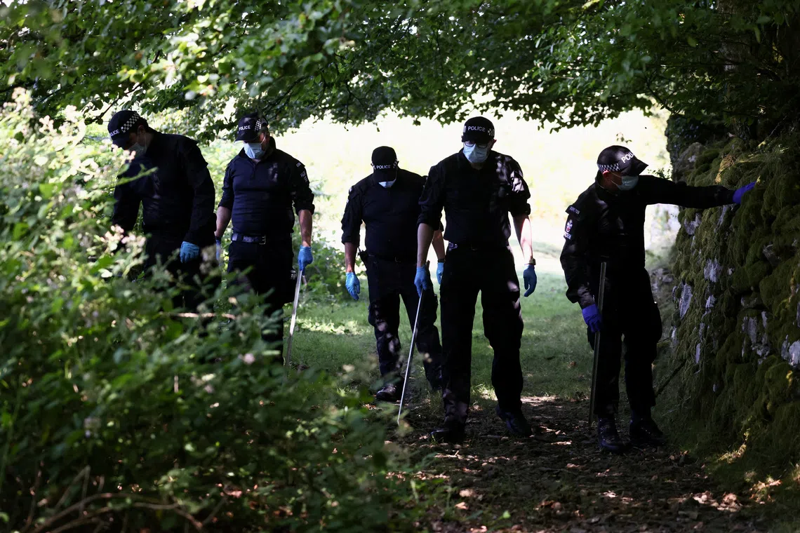 Police officers investigate the area near the home of Ann Widdecombe after she was found dead on July 11.
