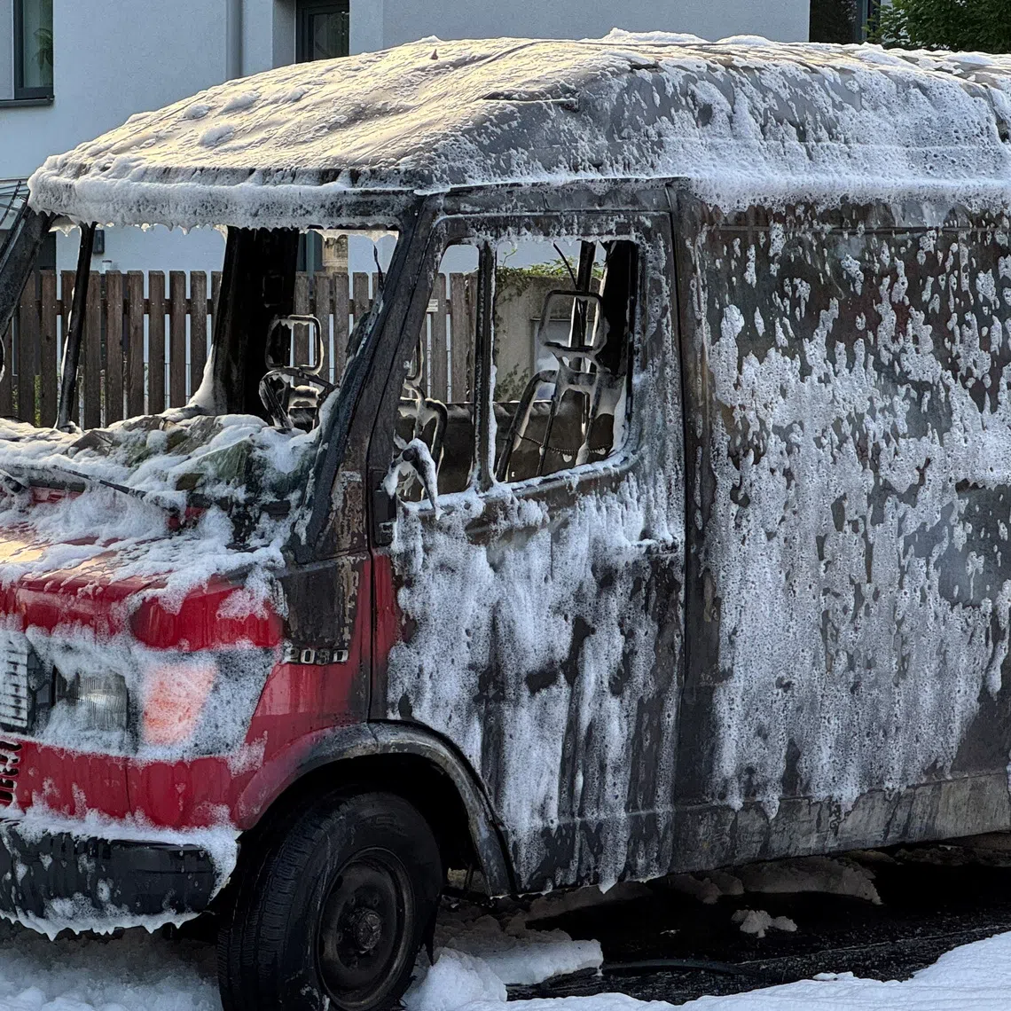 A burnt-out van is covered in foam after being extinguished by fire fighters in Munich, Germany, October 1, 2025. Police and firefighters were out in large numbers along Munich's Lerchenauer Strasse arterial road after a local newspaper reported that explosions and gunshots had been heard.     REUTERS/Ayhan Uyanik