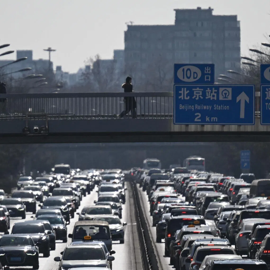 Pedestrians walk along an overpass as traffic snarls in Beijing on Feb 11. 