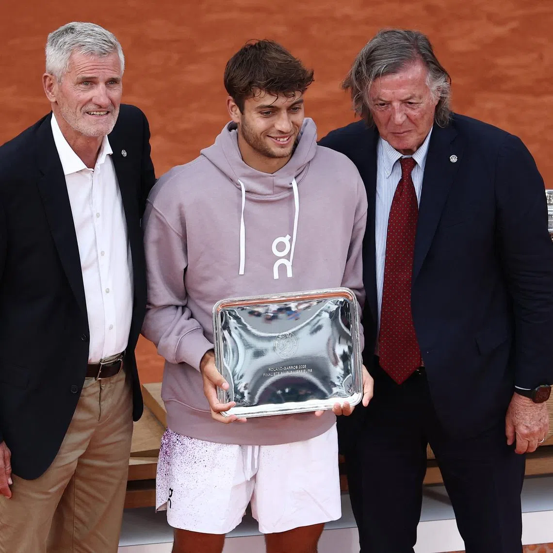 Tennis - French Open - Roland Garros, Paris, France - June 7, 2026 Italy's Flavio Cobolli poses for a photo with the runners up trophy with President of the French Tennis Federation Gilles Moretton and Former Tennis player Adriano Panatta REUTERS/Guglielmo Mangiapane