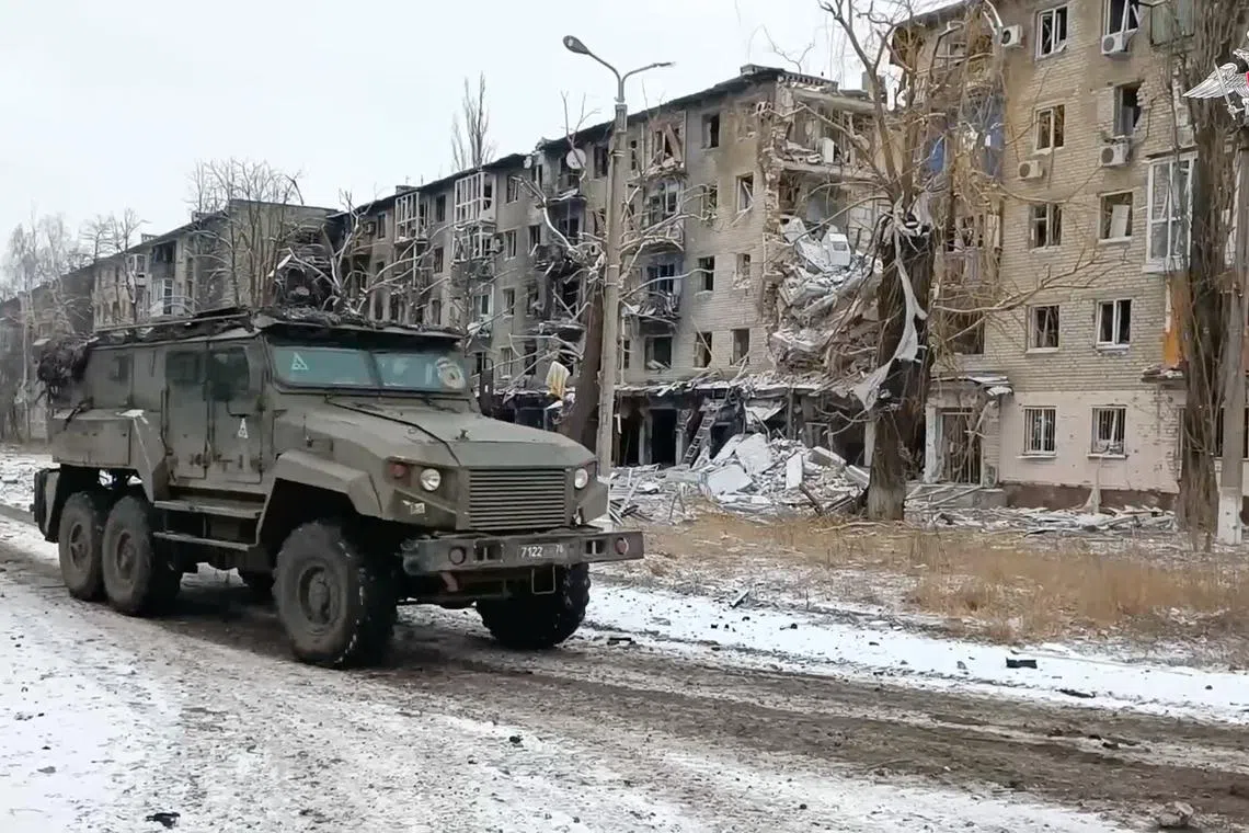 A Russian military vehicle drives past residential buildings damaged in the course of Russia-Ukraine conflict in the town of Avdiivka in the Donetsk Region, Russian-controlled Ukraine, in this image taken from video released February 20, 2024. Russian Defence Ministry/Handout via REUTERS