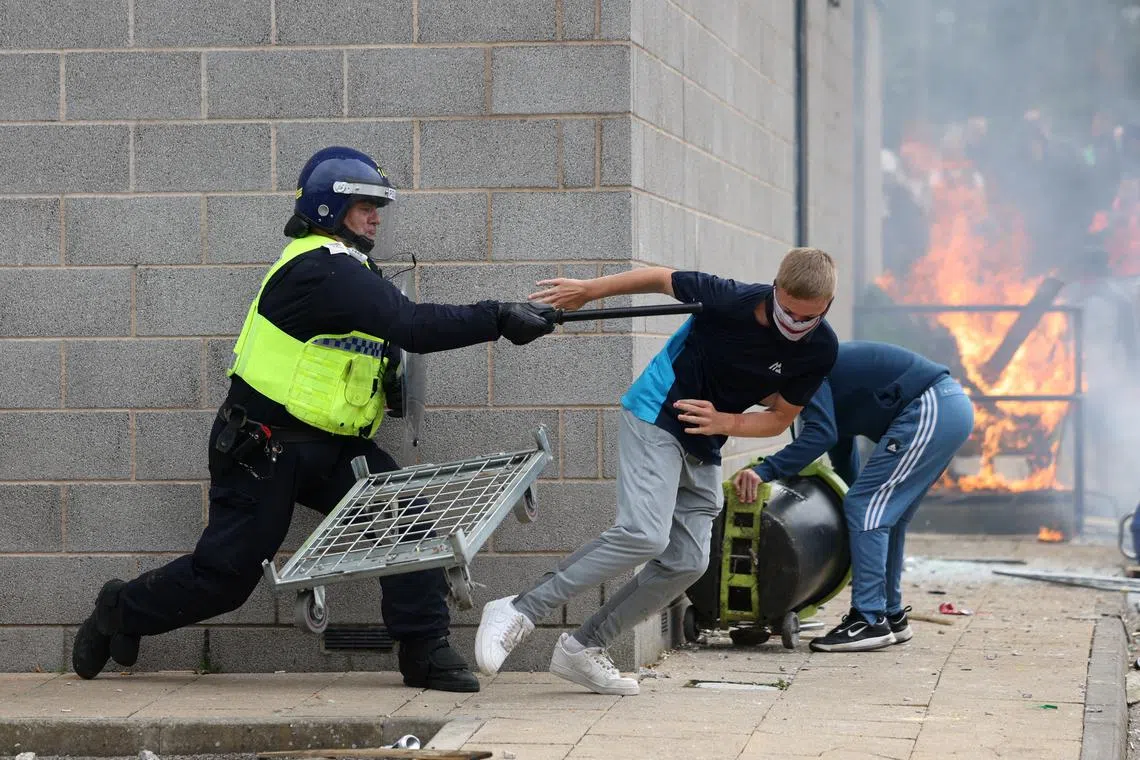 FILE PHOTO: A demonstrator runs away from a police officer during an anti-immigration protest, in Rotherham, Britain, August 4, 2024. REUTERS/Hollie Adams/File Photo