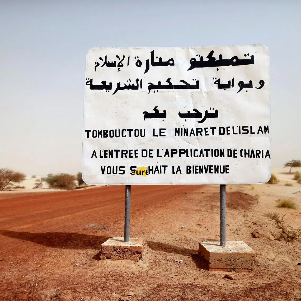 FILE PHOTO: A road sign written by Islamist rebels is seen at the entrance into Timbuktu January 31, 2013. The sign reads, \"Timbuktu, the minaret of Islam and the entrance to the application of the Sharia law welcomes you.\"  REUTERS/Benoit Tessier/File Photo