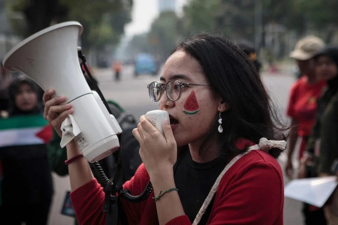 A woman with a watermelon face paint shouts slogans into a megaphone during a protest in solidality with the Palestinian people in front of the US embassy in Jakarta on November 9, 2023. Thousands of civilians, both Palestinians and Israelis, have died since October 7, 2023, after Palestinian Hamas militants based in the Gaza Strip entered southern Israel in an unprecedented attack triggering a war declared by Israel on Hamas with retaliatory bombings on Gaza. (Photo by ADITYA AJI / AFP)